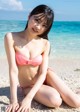 A woman in a pink bikini sitting on the beach.